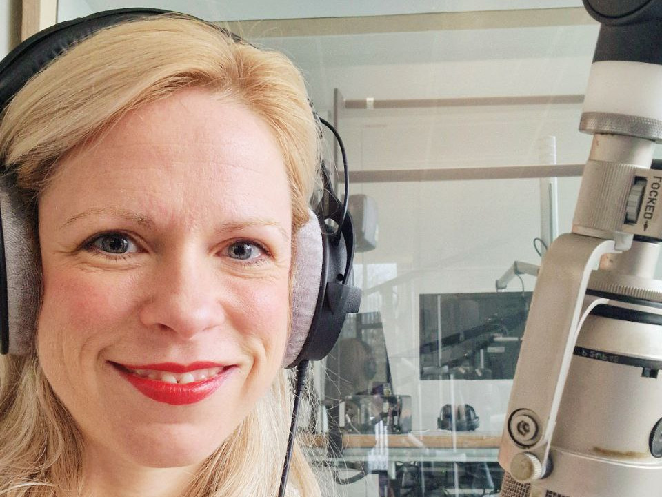 Maria Becker Maria Becker in einem Hörfunk-Studio mit Kopfhörern vor einem Mikrophon.