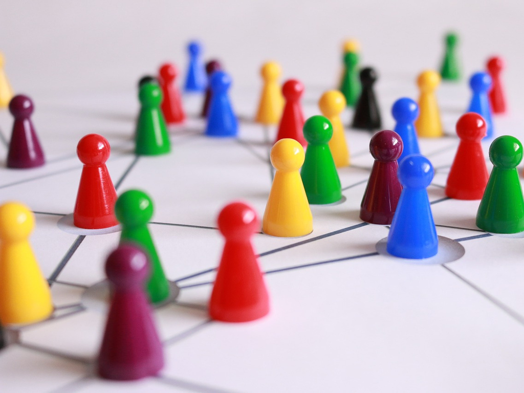 Bunte Spielfiguren auf einer weißen Oberfläche. Die Figuren sind mit schwarzen Strichen auf der Oberfläche teilweise miteinander verbunden.